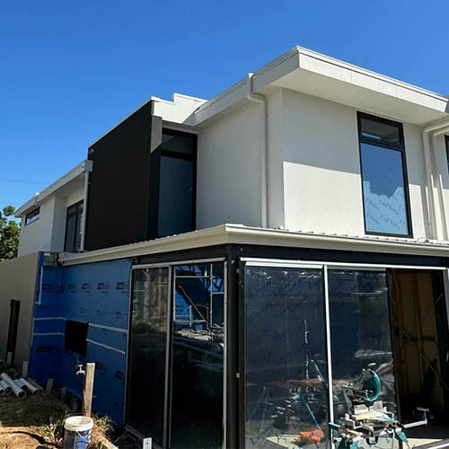 1-home-about-s2 Two-storey house under construction with fresh white render and building wrap below