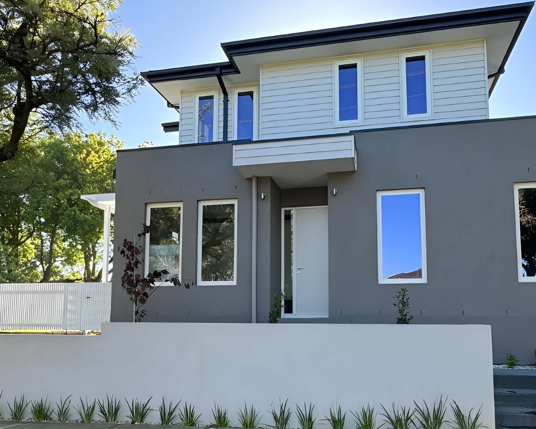 1-home-enhancing Front of a two-storey home with grey rendered ground floor and rendered front wall